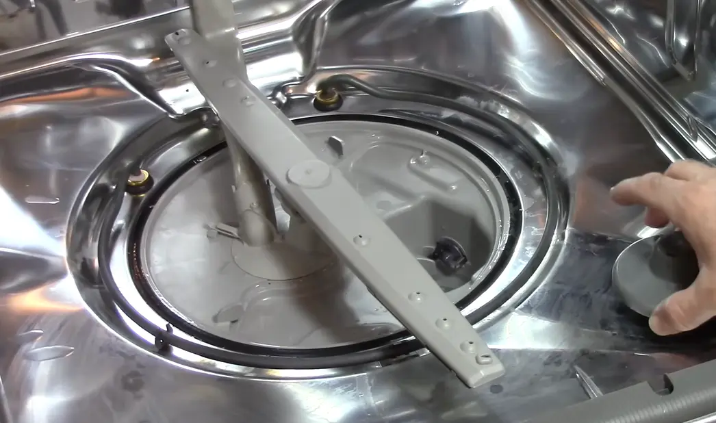 Technician inspecting dishwasher spray arm and drain assembly inside a stainless steel dishwasher in Lexington KY
